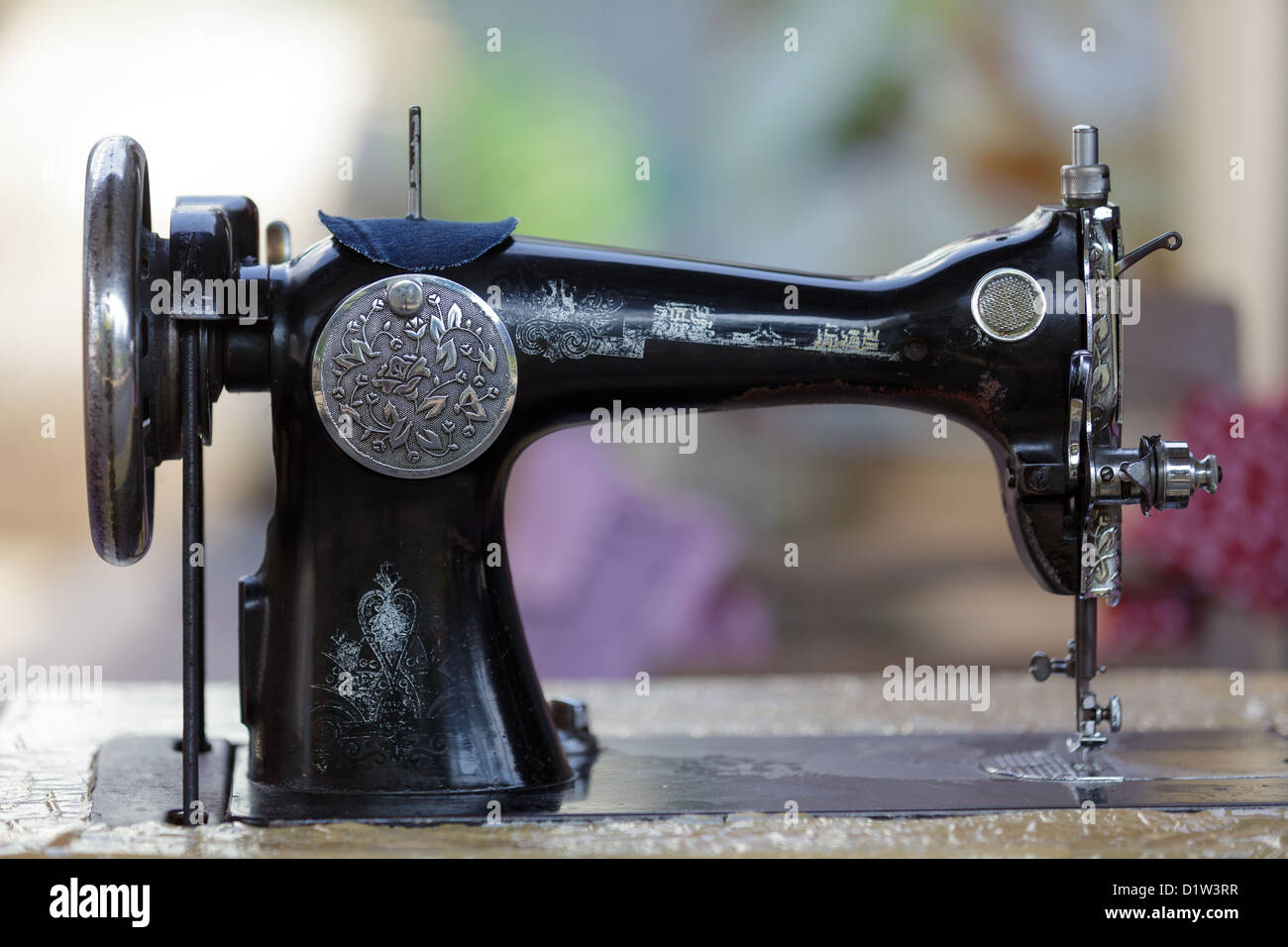 Old traditional metallic sewing machine with many asian decorations, Thailand Stock Photo