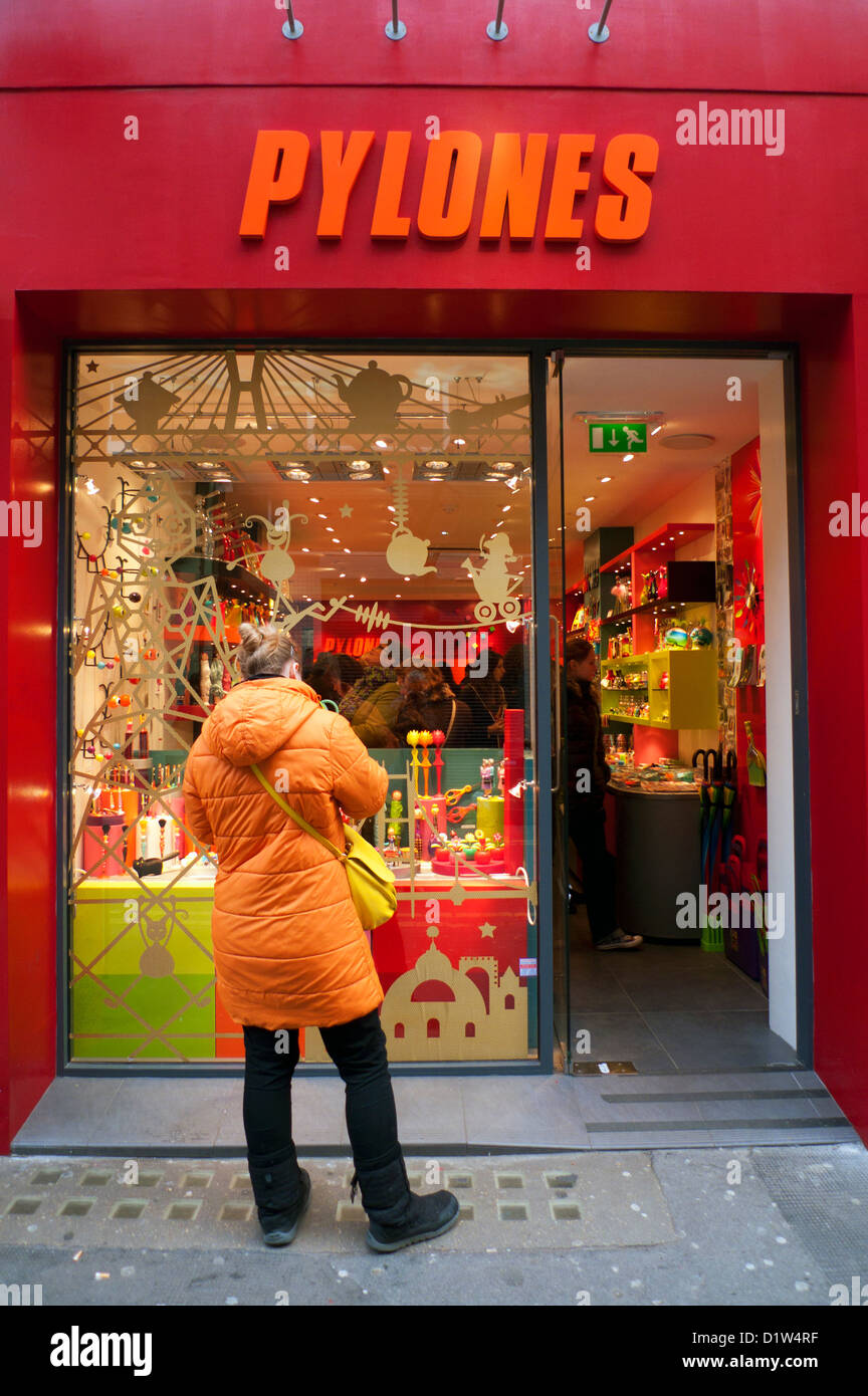 A female shopper in a puffy orange coat looking in the window of