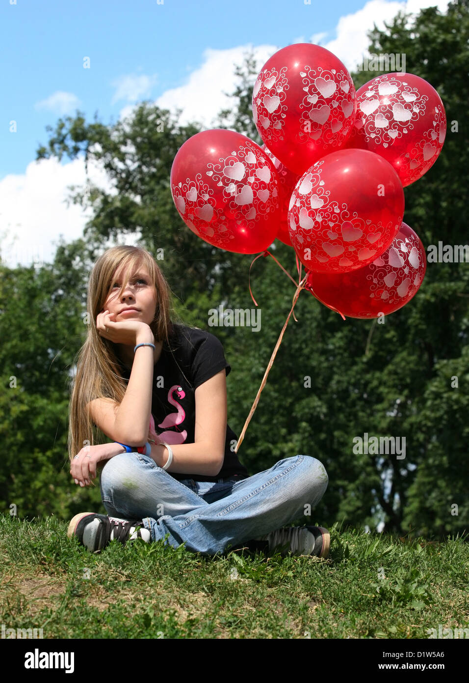 The girl - teenager sits on a grass with red balloons Stock Photo - Alamy