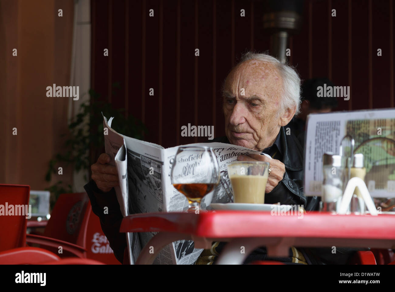 Spain, Andalucia - gentleman reading English language newspaper with a coffee and brandy, Costa del Sol. Stock Photo
