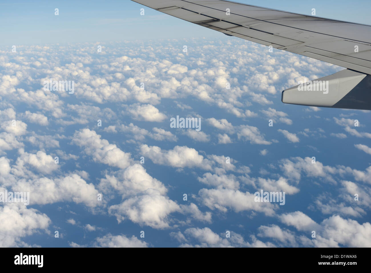 Commercial airliner wing above the clouds, view from window Stock Photo