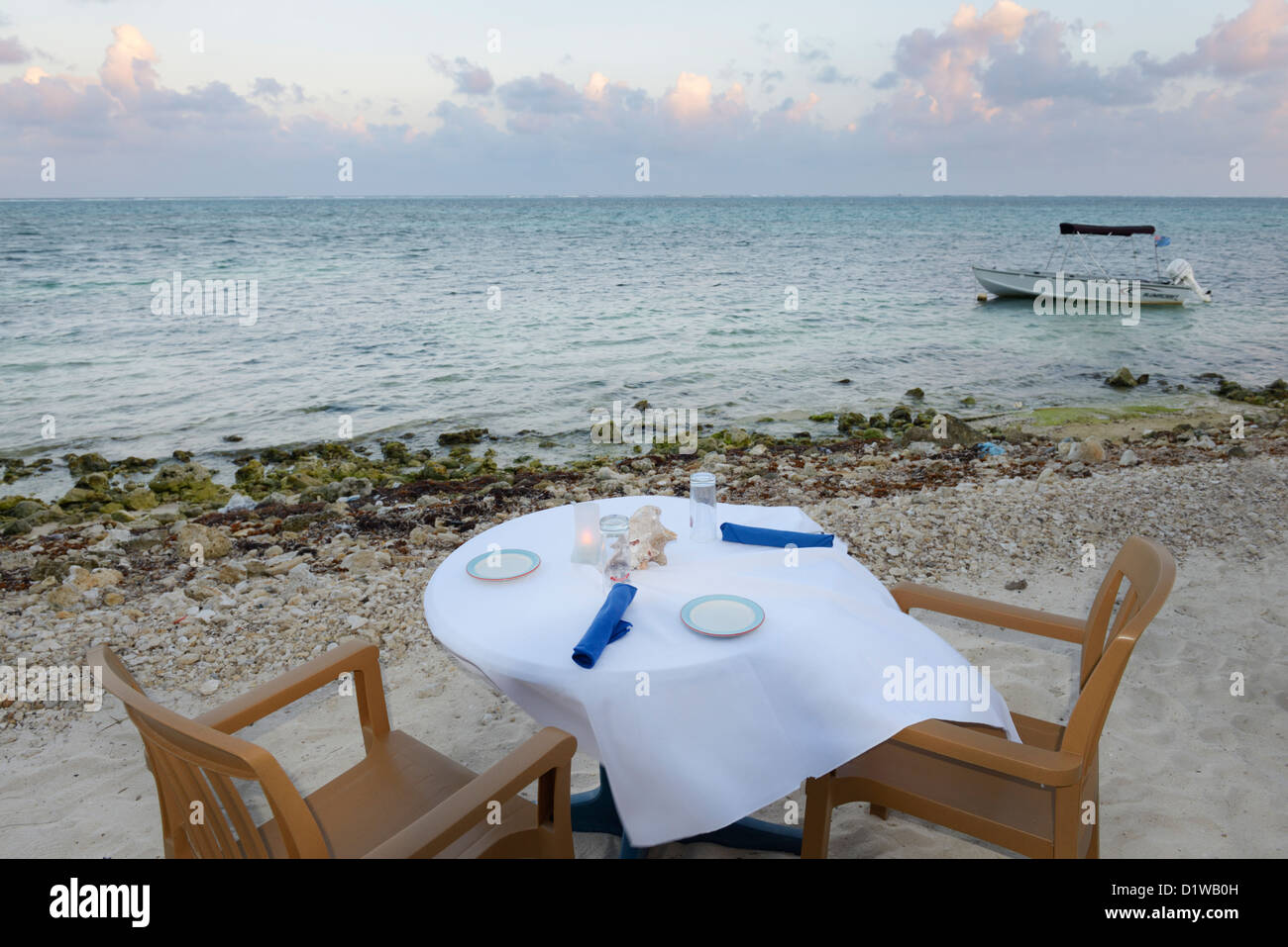 Restaurant table on beach at sunset over the Caribbean, East End of Grand Cayman. Stock Photo