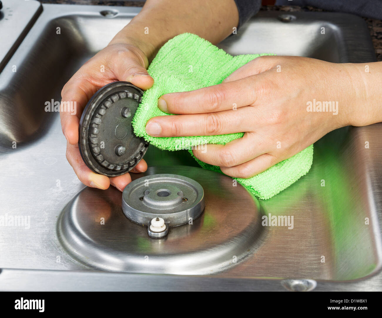 Hands with microfiber cloth cleaning gas stove burner cover Stock Photo