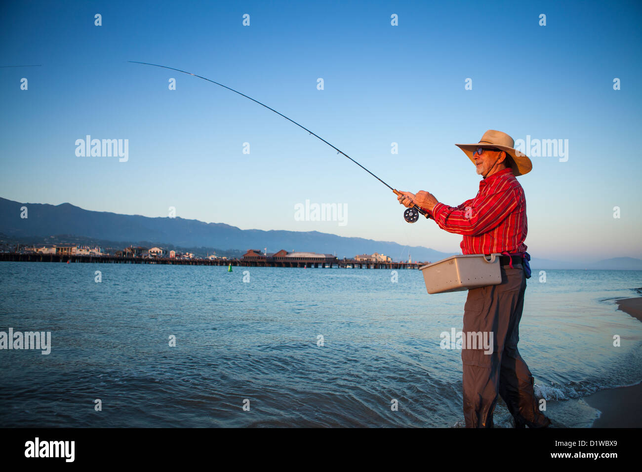 Saltwater flyfisherman casting for surf perch with the wharf in the background, harbor sandbar, Santa Barbara, California Stock Photo