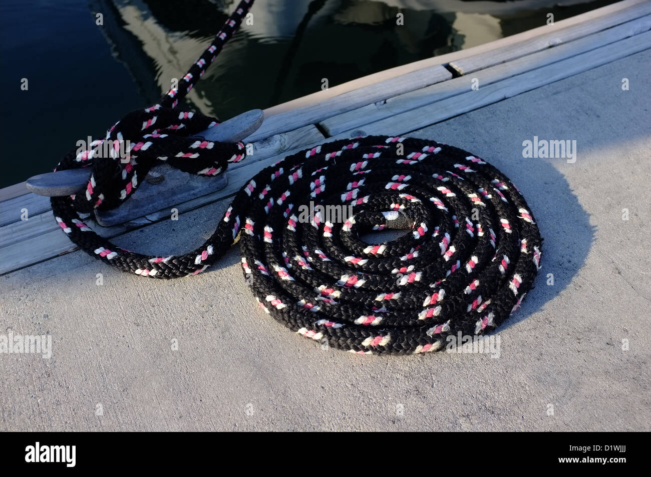 A black, pink and white boat mooring line coiled on the finger birth at the Royal Phuket Marina Thailand Stock Photo