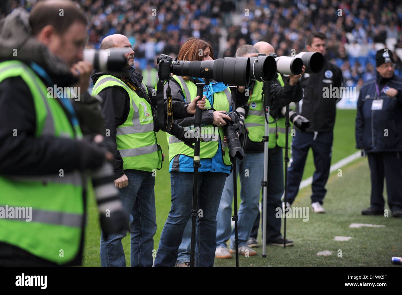Professional sports photographers with telephoto lenses at a football