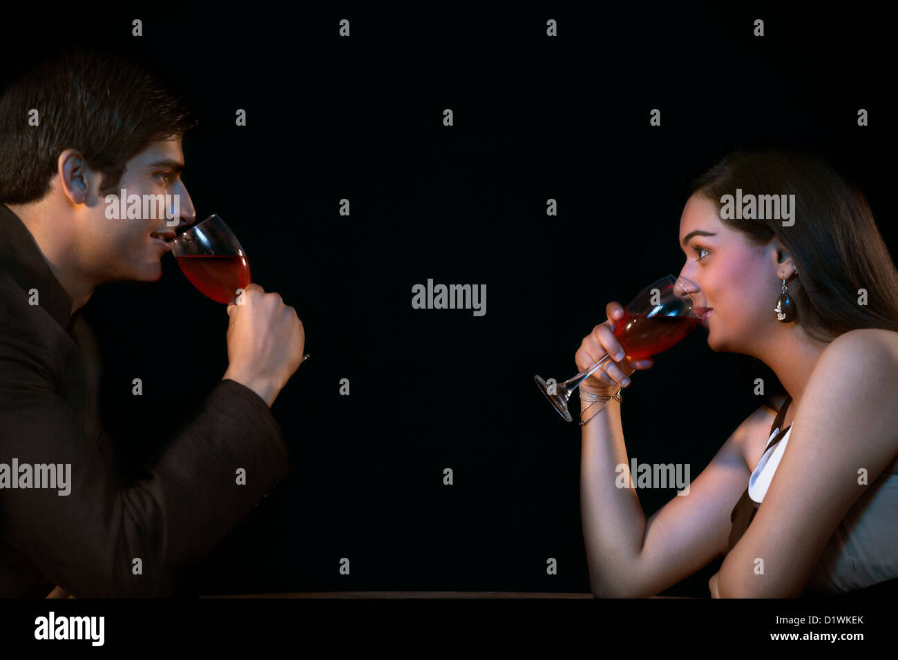 Side view of young couple drinking red wine Stock Photo - Alamy