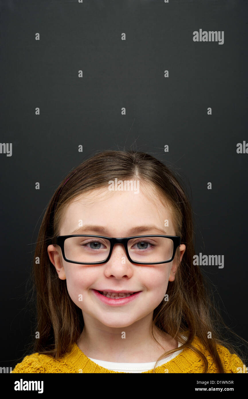 Smart young girl wearing a yellow jumper and glasses stood in front of