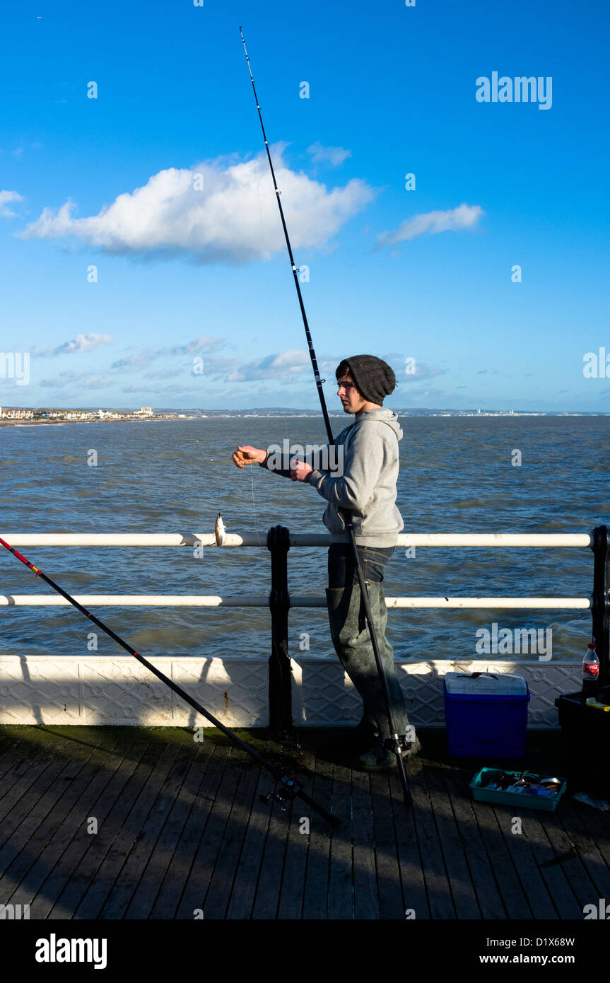 A young man catches a small whiting on Worthig Pier Stock Photo