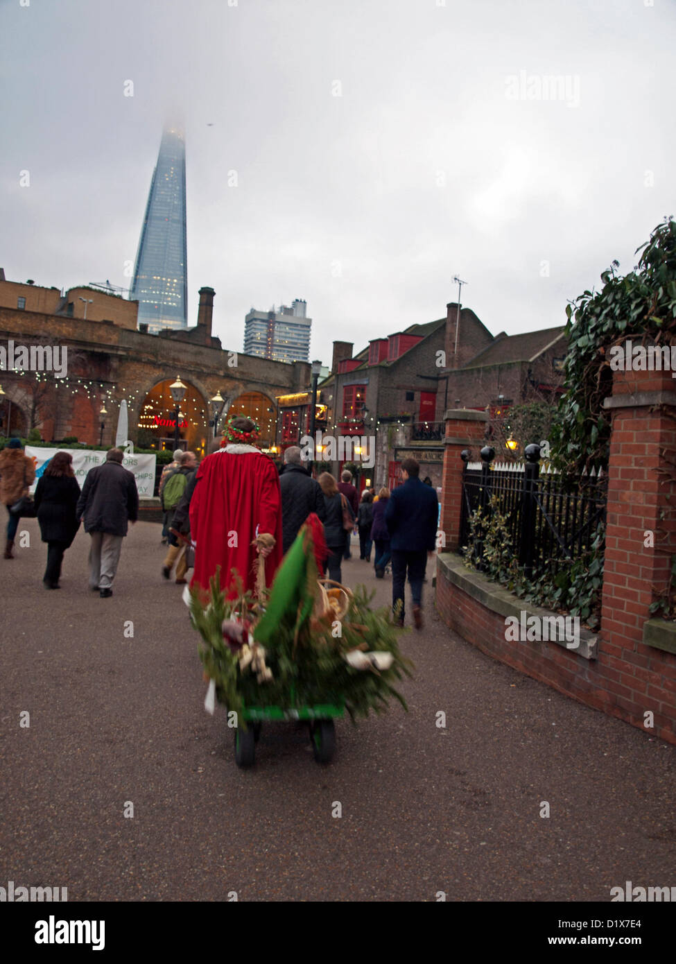 Crowds being led to the historic George Inn in Borough High Street as part of celebrations during the Twelfth Night festival on 6th January, 2012 showing the Shard London Bridge in the background, Bankside Riverwalk, London, England, UK. The Twelfth Night is a free annual seasonal celebration held in the Bankside area of London. It is a celebration of the New Year, mixing ancient seasonal customs with contemporary festivity. Stock Photo