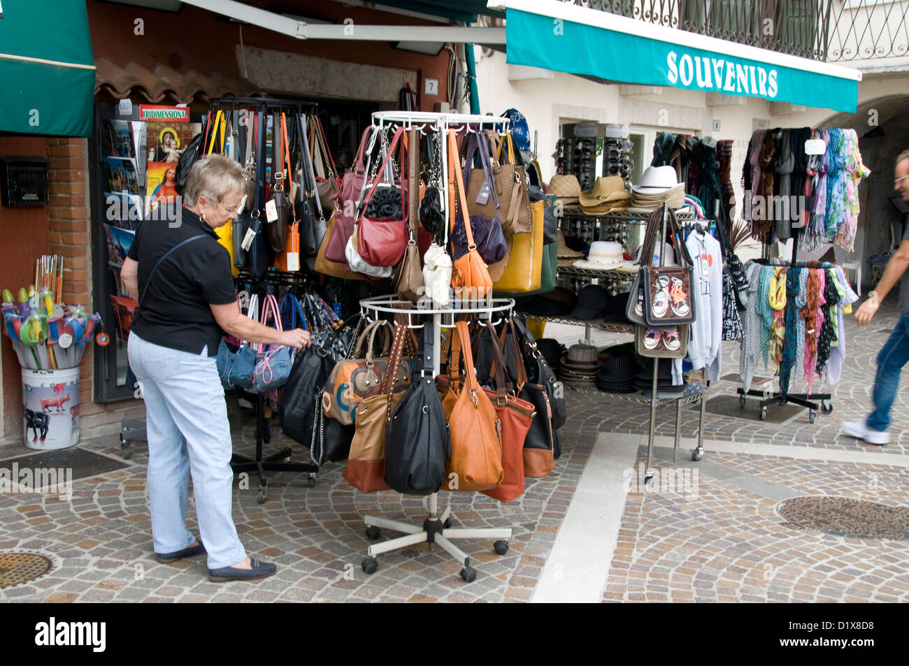 A tourist browse through a selection of leather handbags on sale at an souvenir’s shop in a small town on Lake Garda in northern Italy Stock Photo
