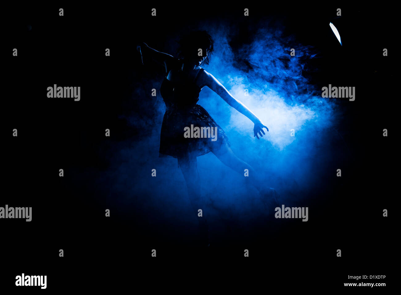 A young woman dancer dancing in blue lit smoke smoky studio Stock Photo