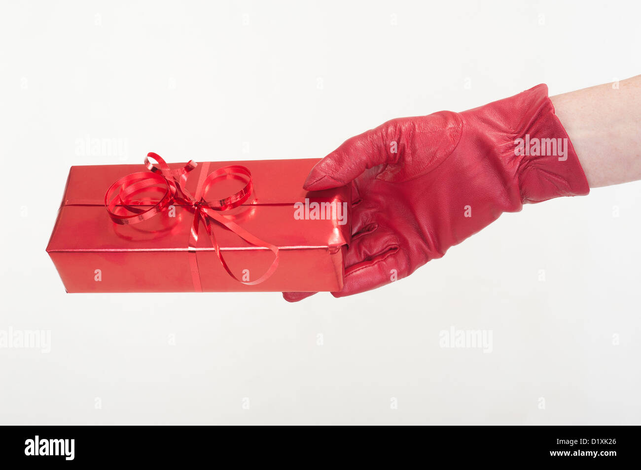 Gift wrapped in red paper and held in a woman's gloved hand Stock Photo