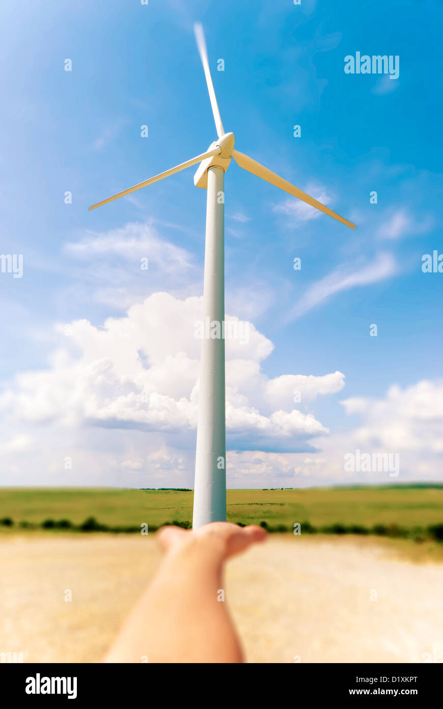 Stock Photo of hand holding a windmill. Background a blue sky with clouds Stock Photo