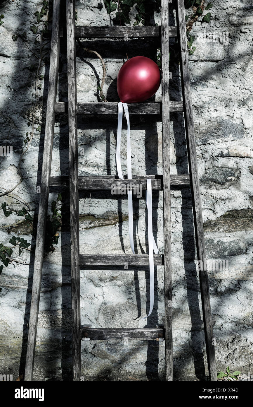 a red balloon on an old wooden ladder Stock Photo