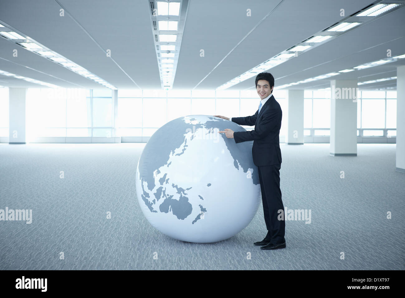 a businessman looking into a huge globe in an empty room Stock Photo ...