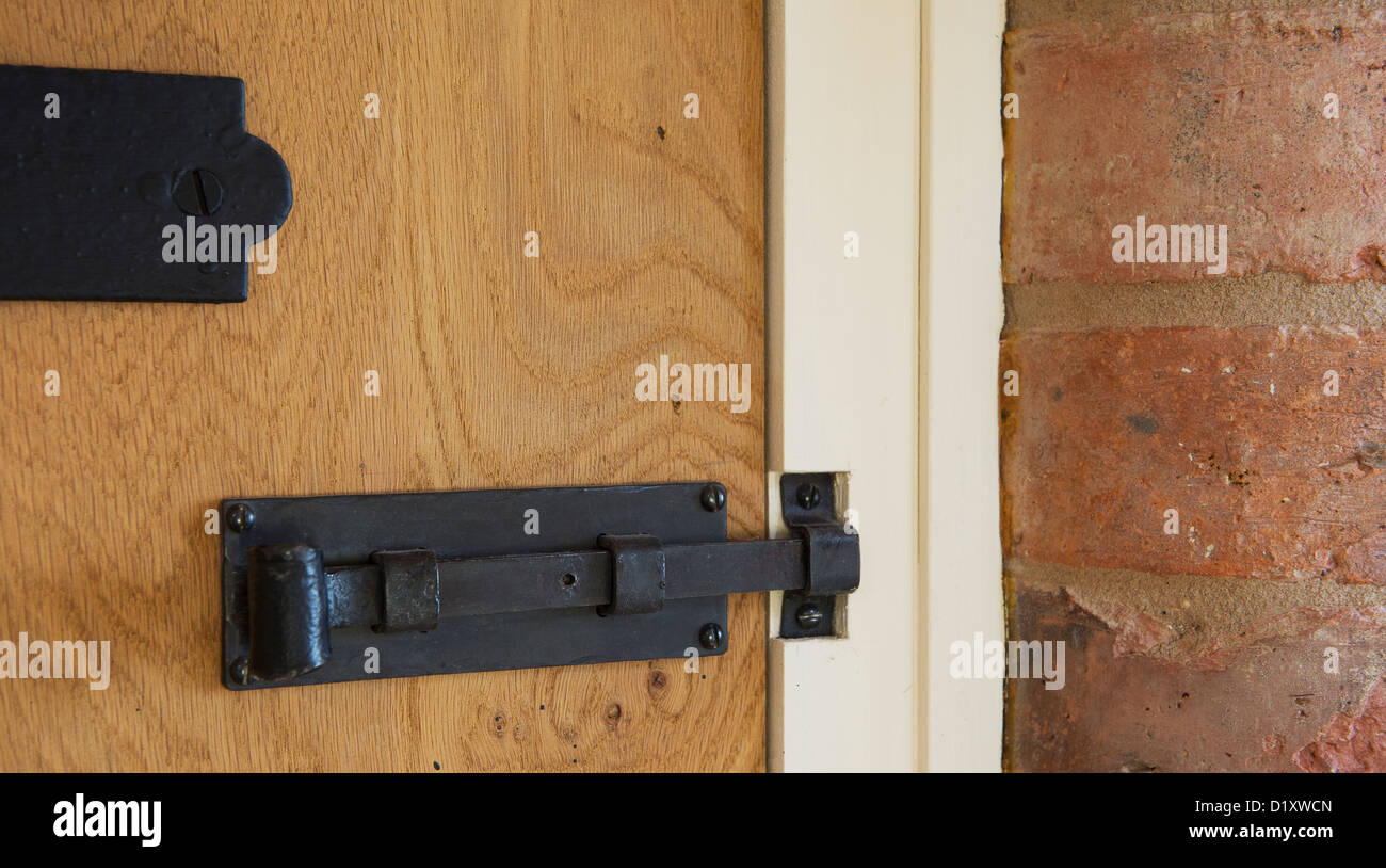 Black cast iron hinges and bolt on a new door in a newly built property