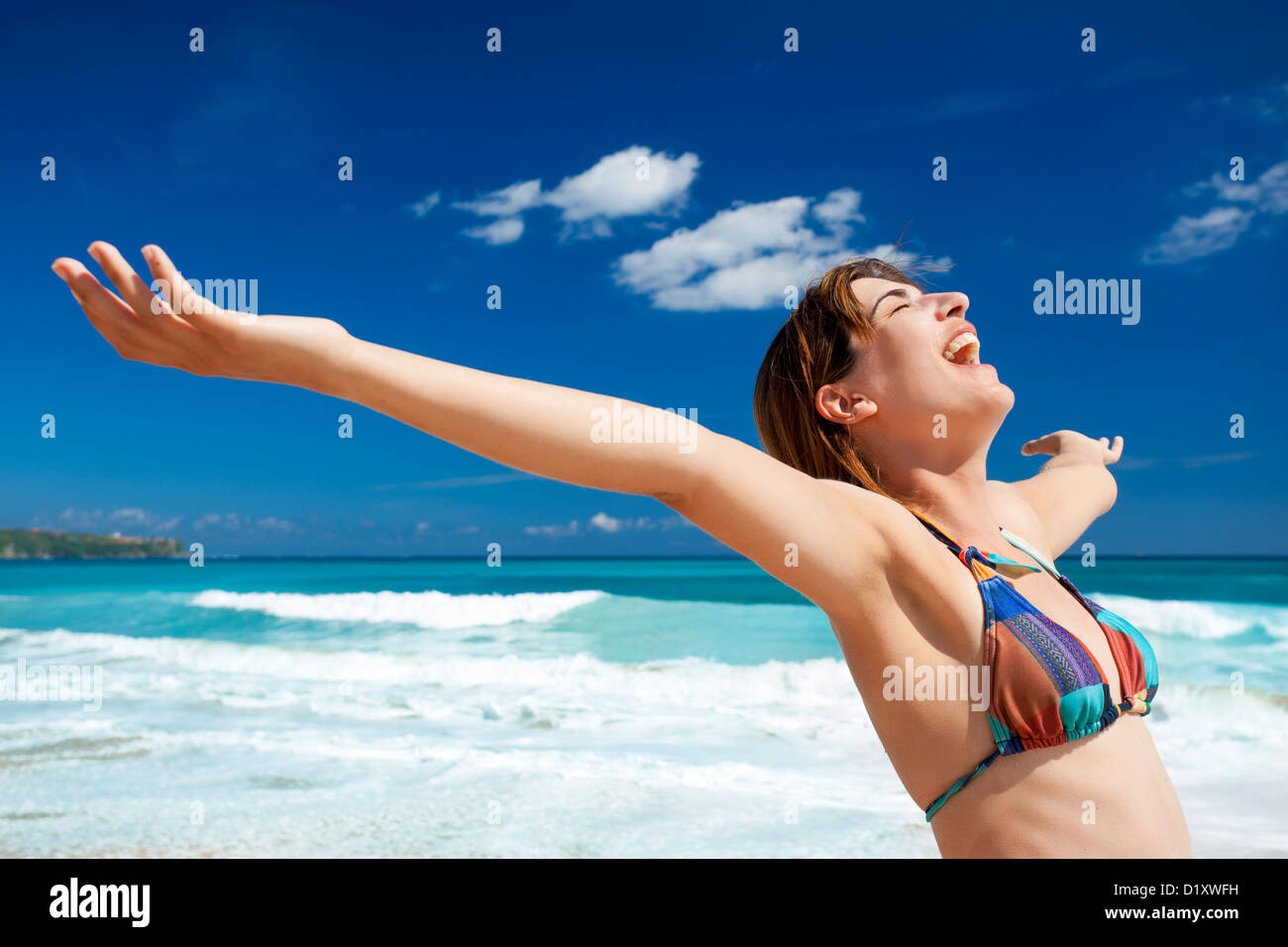 Beautiful young woman with arms open in a tropical beach enjoying the summer Stock Photo