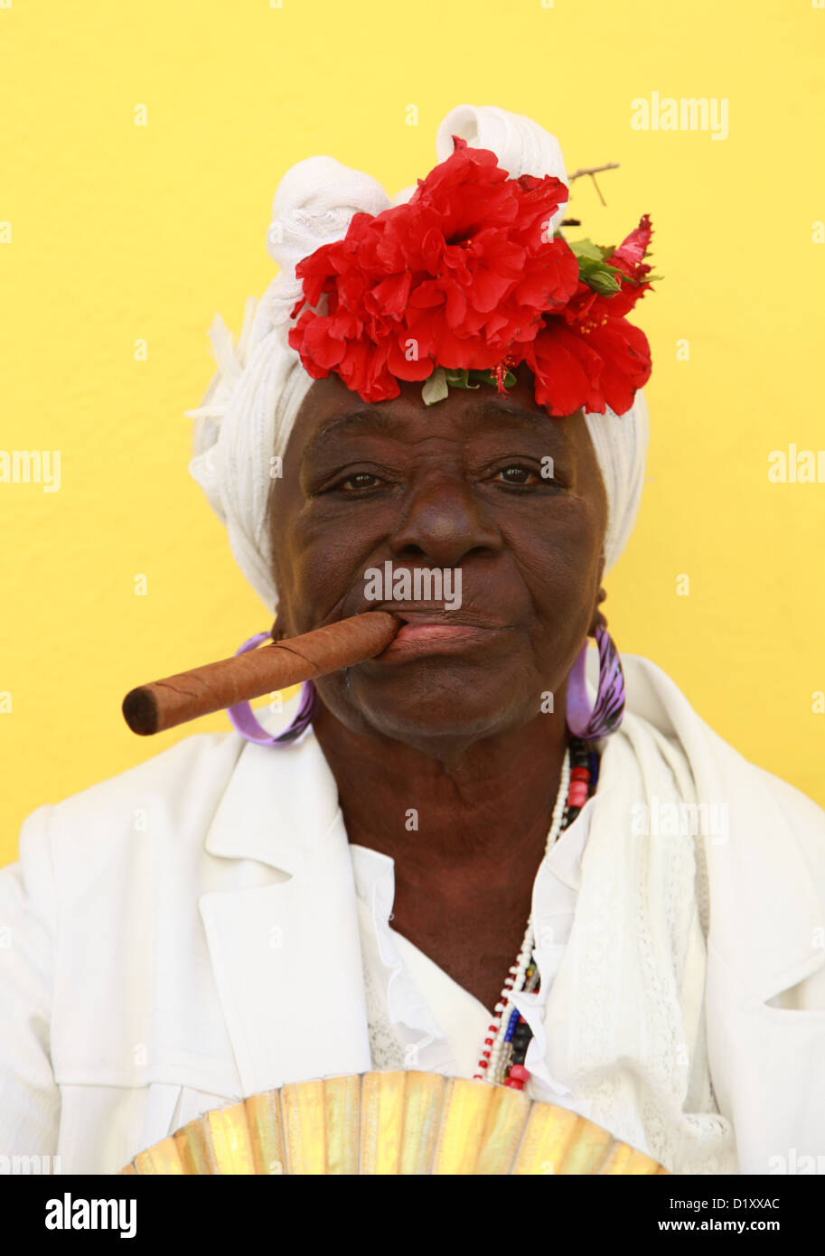 Cuban woman wearing a Santeria white dress smoking a big cigar La Habana Vieja Havana Cuba Stock Photo