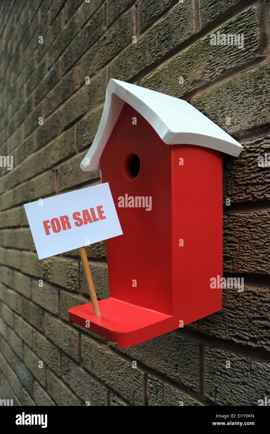 WALL MOUNTED BIRD BOX HOUSE WITH FOR SALE SIGN RE MOVING HOUSE MORTGAGES LOANS PRICES COSTS BUYING BUYERS THE ECONOMY SELLING UK Stock Photo