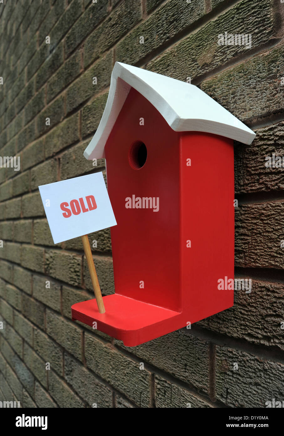 WALL MOUNTED BIRD BOX HOUSE WITH SOLD SIGN RE MOVING HOUSE MORTGAGES LOANS PRICES COSTS BUYING BUYERS THE ECONOMY SELLING LET UK Stock Photo