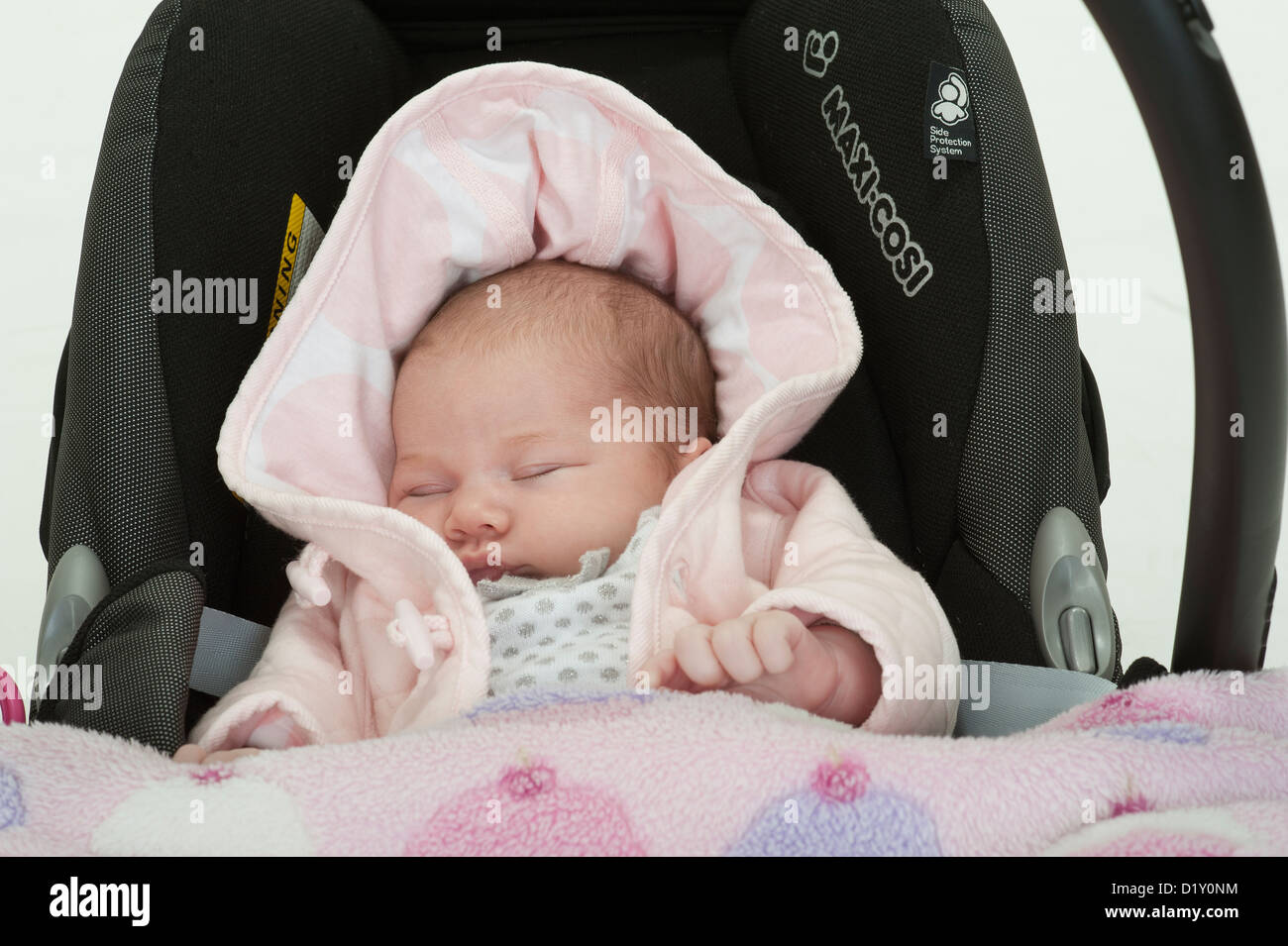 Portrait of a four week old baby girl in a car seat sleeping Stock