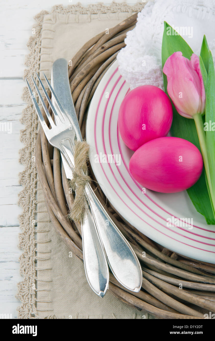 Easter dinner setting with two pink eggs and tulip, rustic white wooden background Stock Photo
