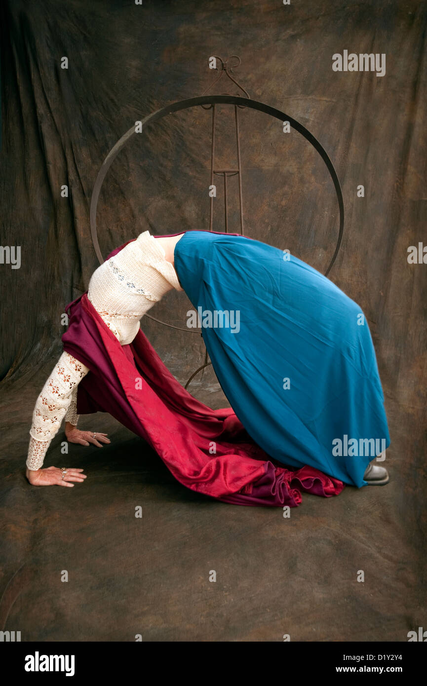 Wise Woman Red Riding Hood. Mature woman in a deep acrobatic backbend in a studio environment. Stock Photo