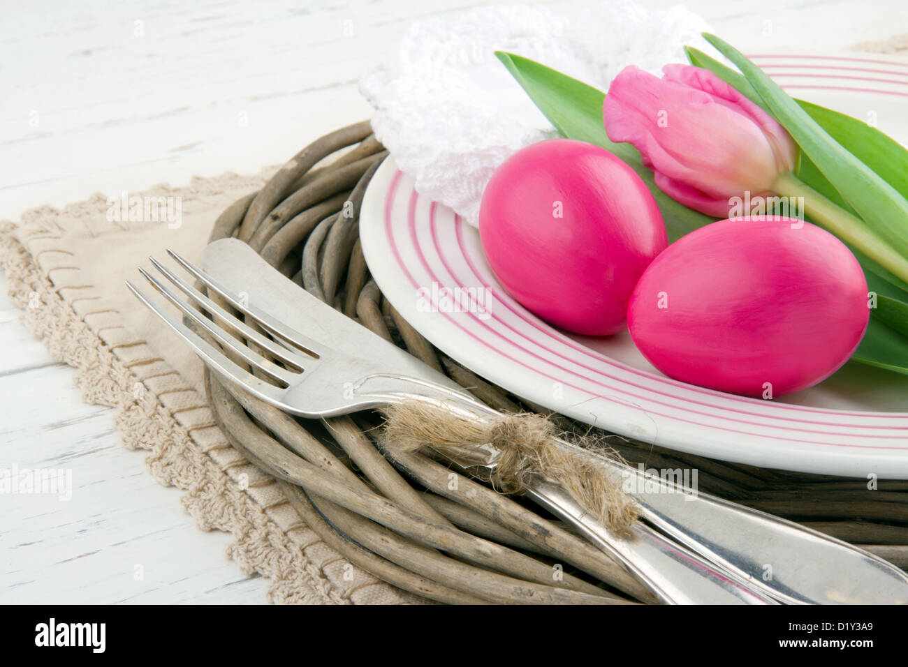 Easter dinner setting with two pink eggs and tulip, rustic white wooden background Stock Photo