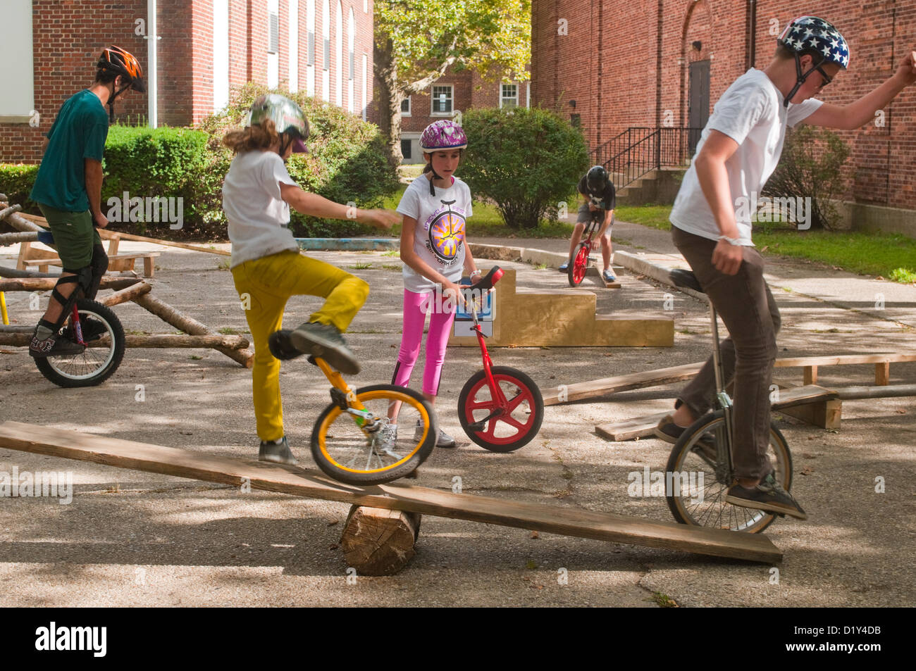 Children practice unicycle tricks on a make shift see saw during the