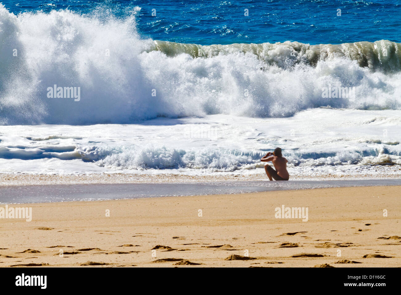 A young man takes a picture of crashing surf on a beach near Todos Santos, Baja, Mexico Stock Photo