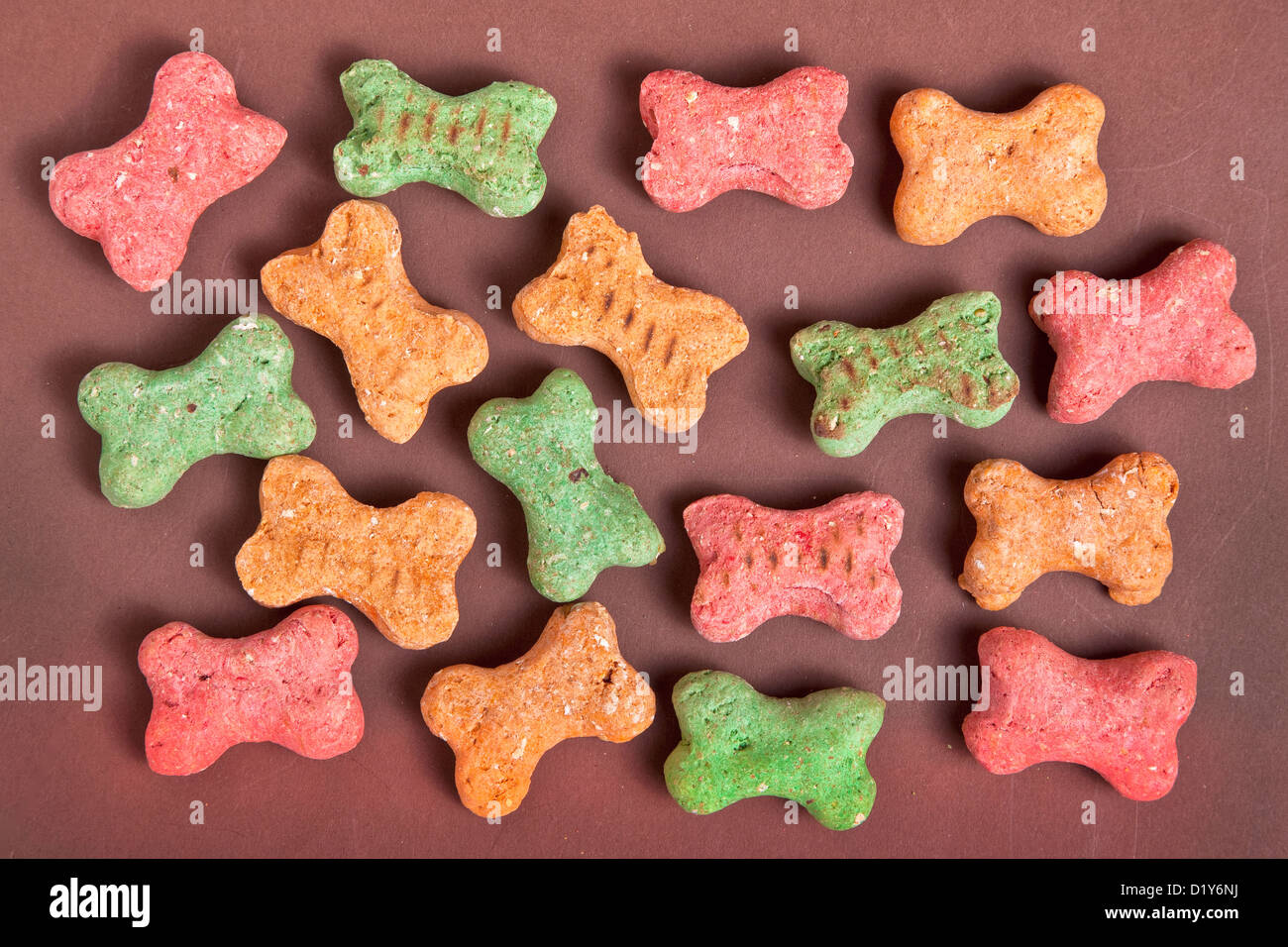 Small multi colored dog biscuits scattered at random on a brown background Stock Photo - Alamy