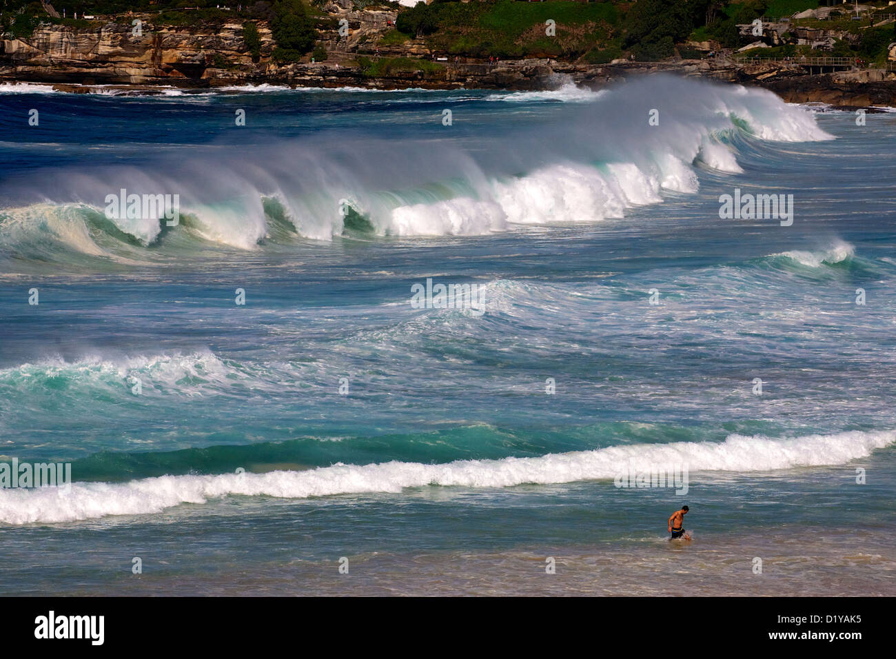 a single person walking out of a strong surf. Stock Photo