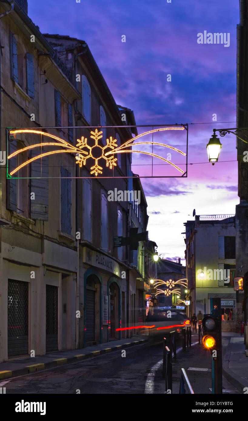 A winter evening street scene of neon lights and a purple sky found in the town of Arles in Southern France. Stock Photo