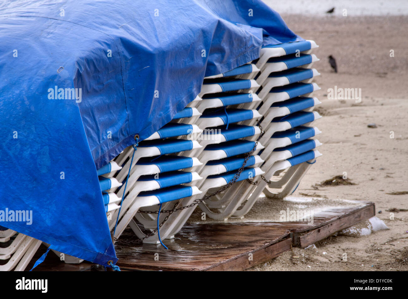 A stack of wet deck chairs on the deserted beach in the stormy