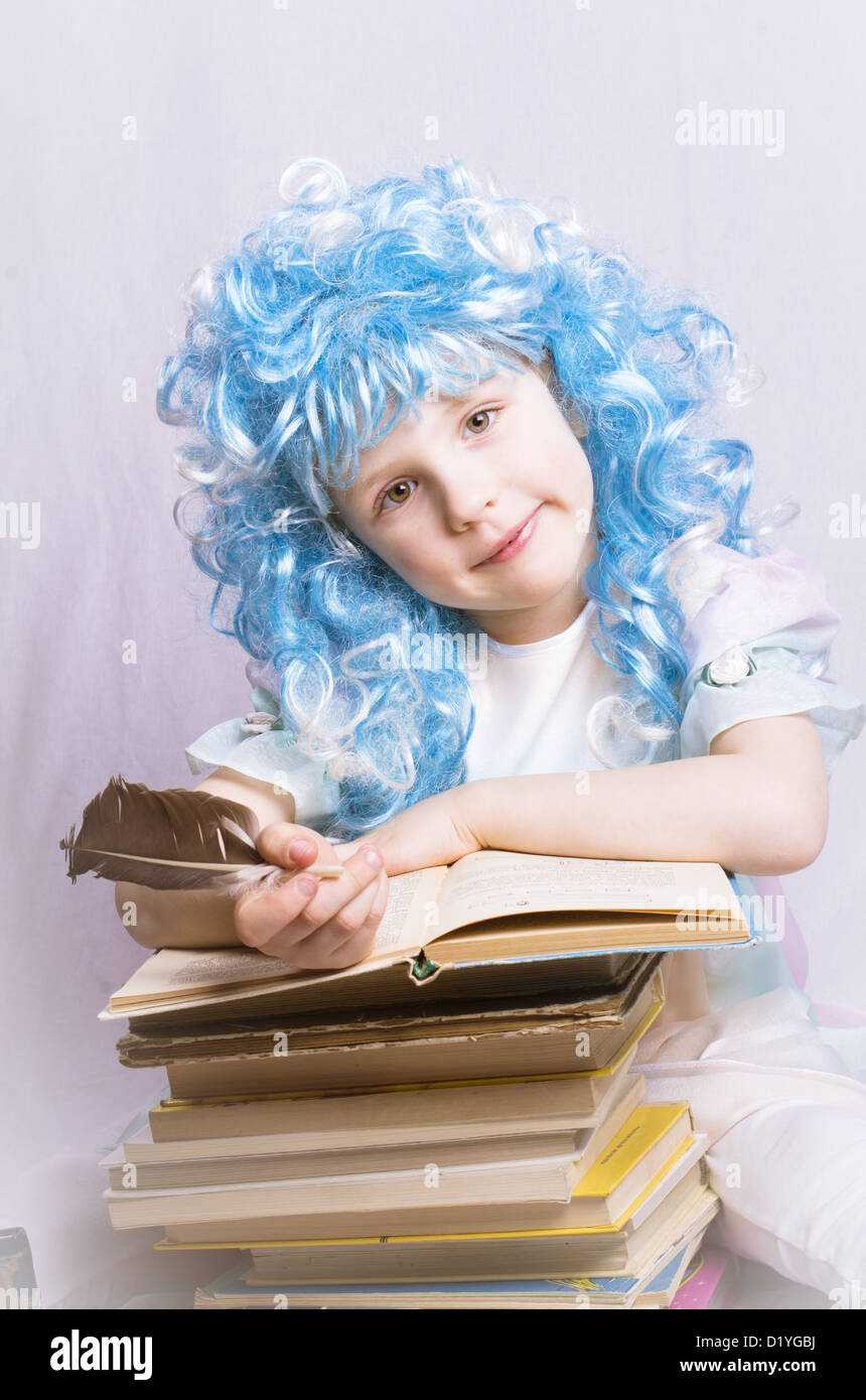 little girl with blue hair and quill pen sitting near stack of books Stock Photo