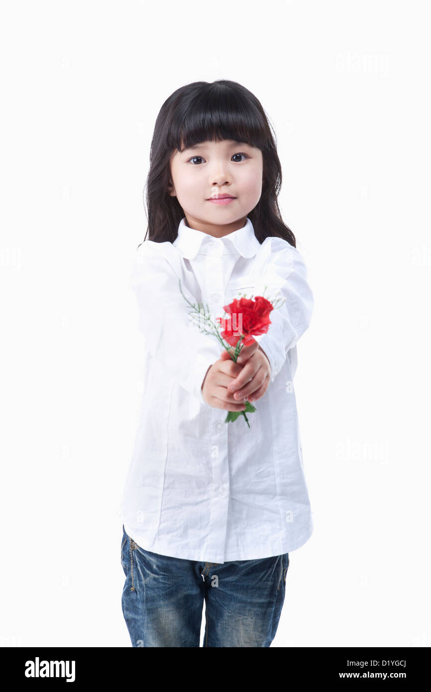 a young girl in a white shirt giving a red flower to you Stock Photo