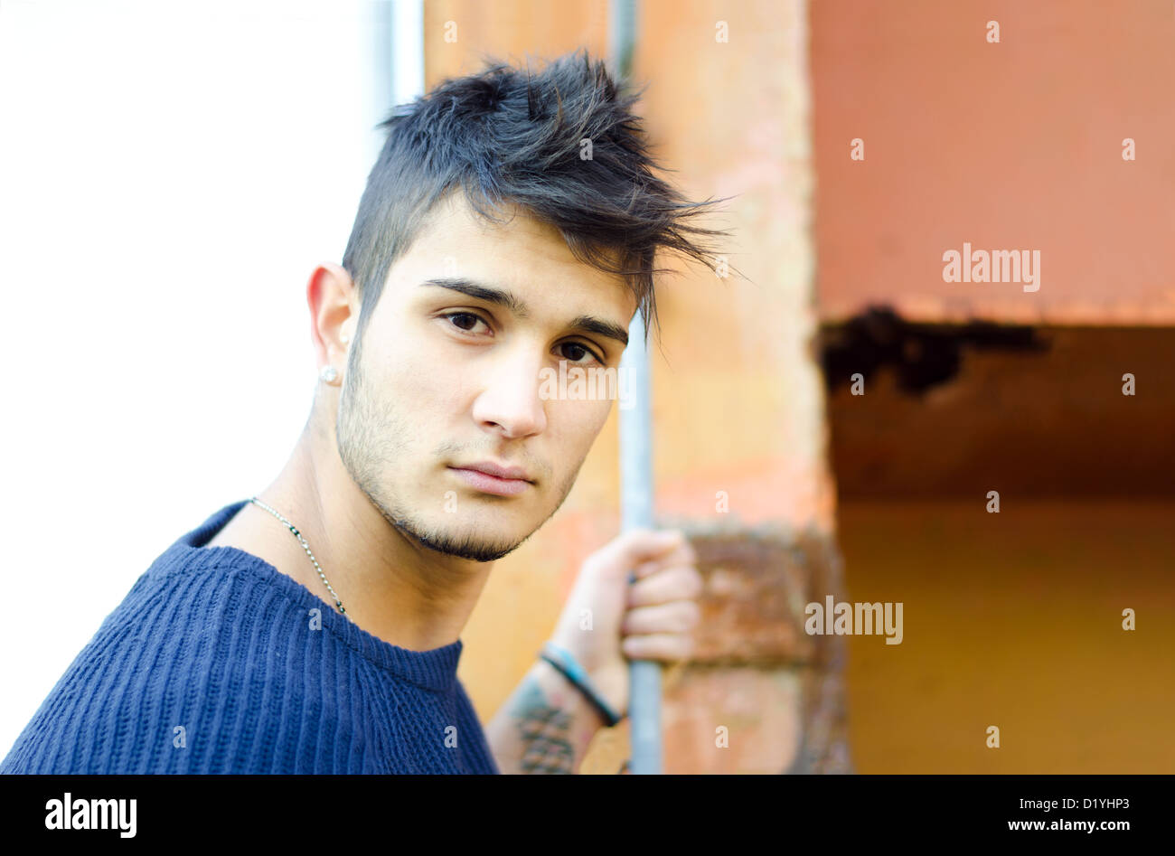 Handsome young man in urban or industrial setting with rusty metal structure Stock Photo