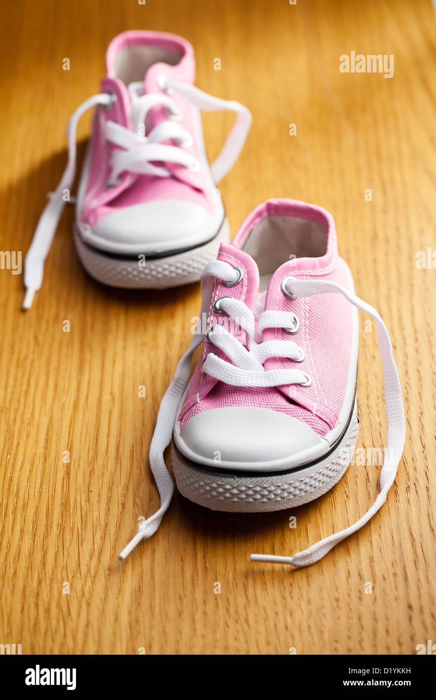 pink baby sneakers on wooden floor Stock Photo - Alamy
