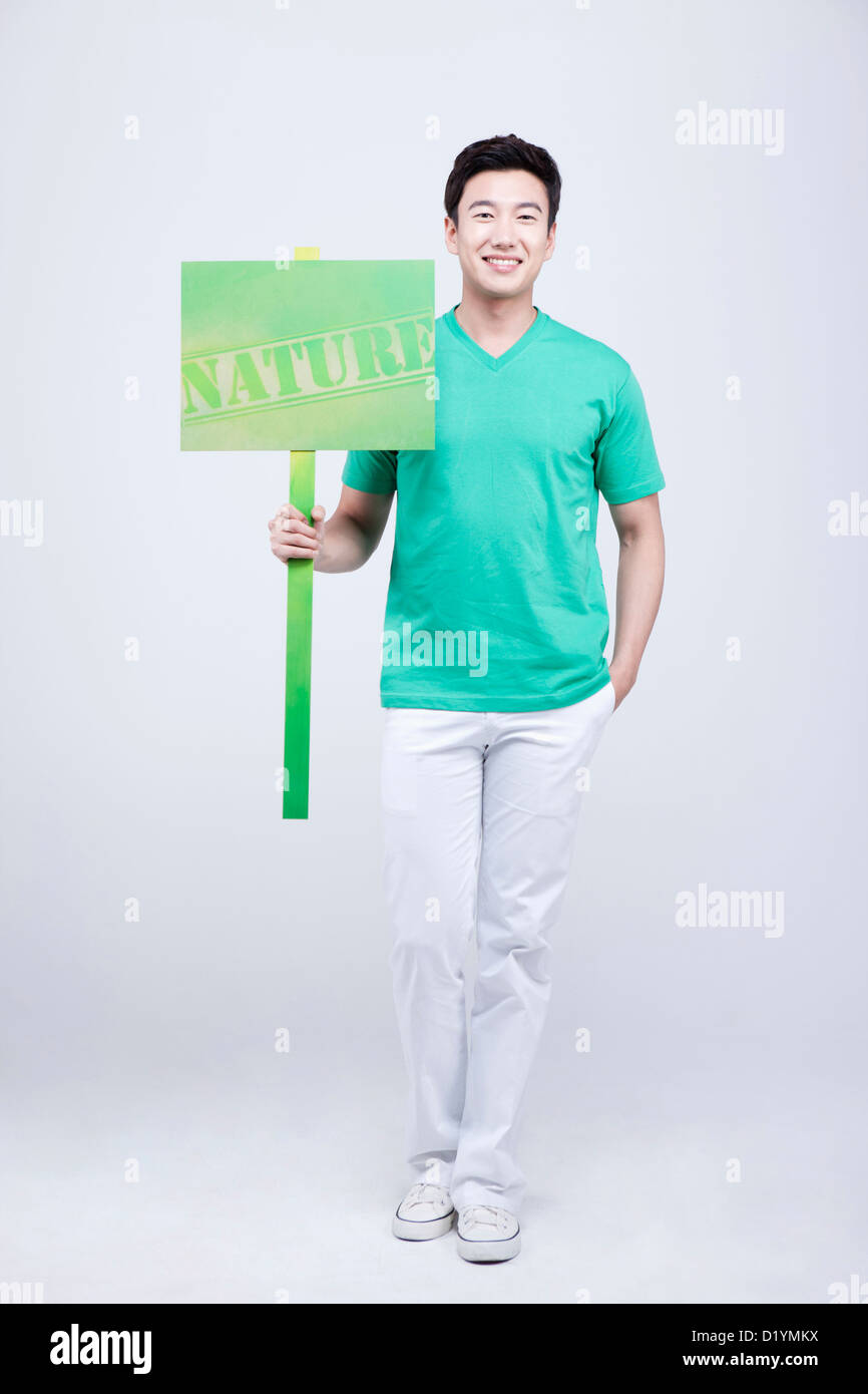 a man in green t-shirt holding a picket with nature sign Stock Photo
