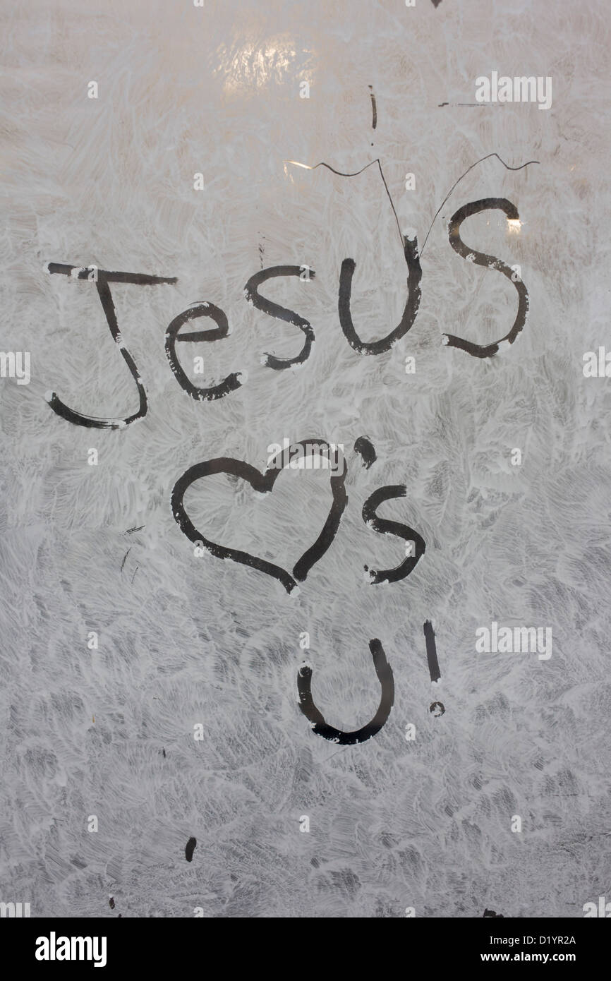 'Jesus Loves (heart) You' handwritten on an opaque window, swirled with emulsion paint, of a new soon-to-open business. The Christian message tells the passer-by in this London street of Jesus' affection for anyone, anywhere. The shop (store) is now closed, a victim of the UK recession and its window has been smeared with the watered-down paint to help obscure the interior. Stock Photo