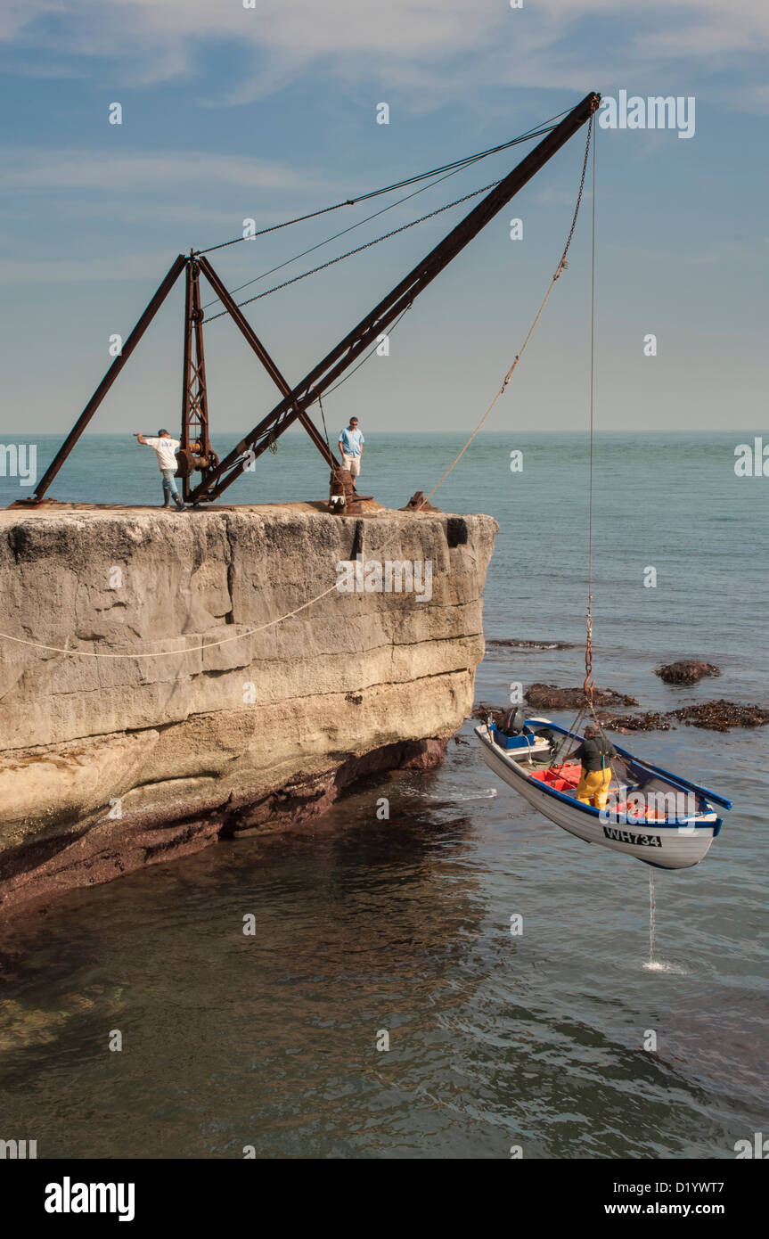 Fisherman on Portland Bill, lifting a boat from the sea Stock Photo