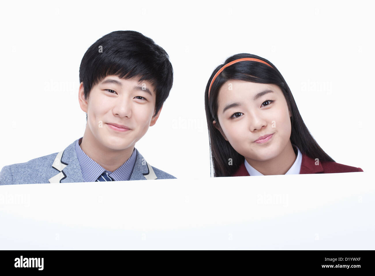 a male and female students with school uniform holding an empty paper ...