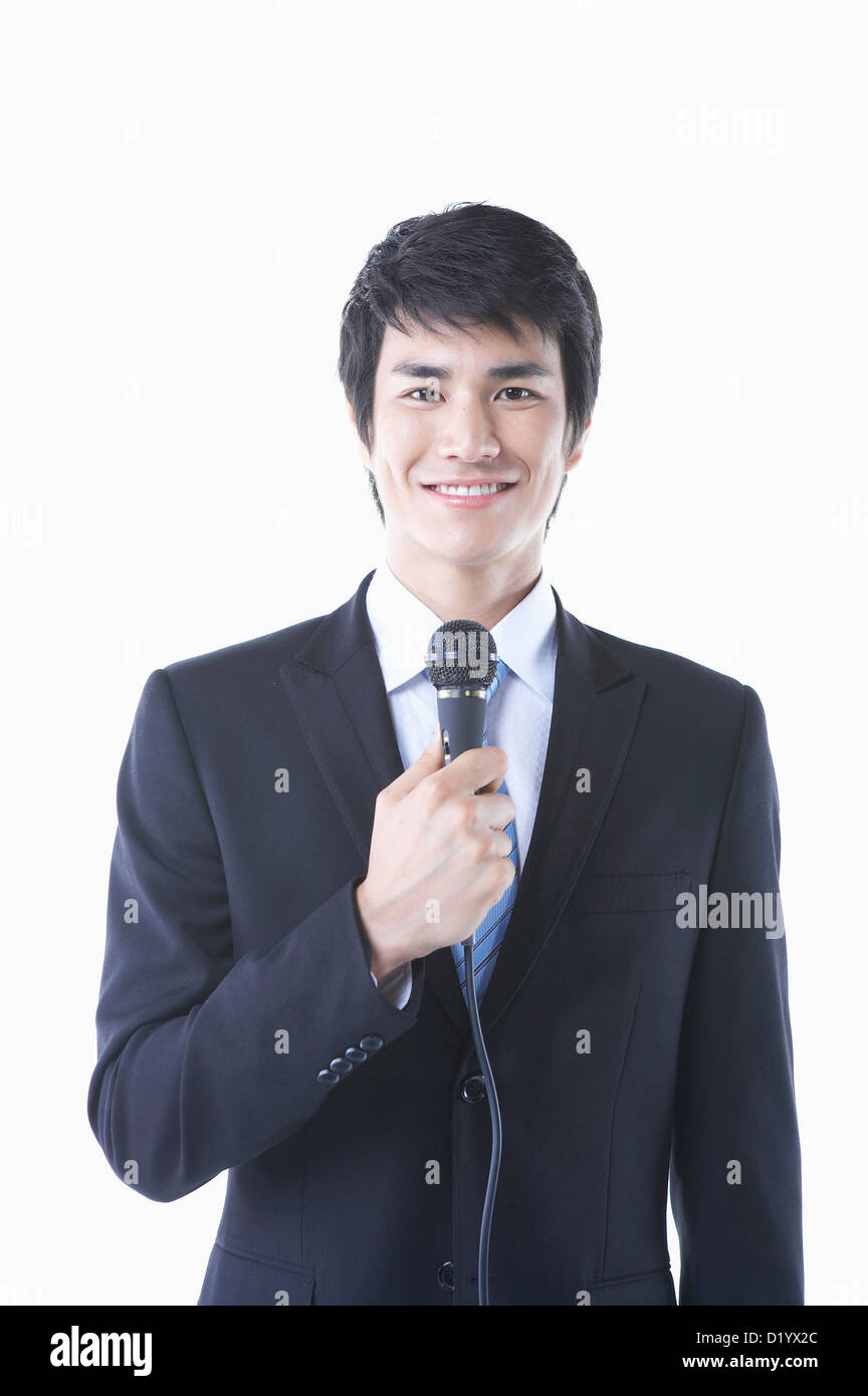 a businessman in a black suit holding a microphone smiling Stock Photo