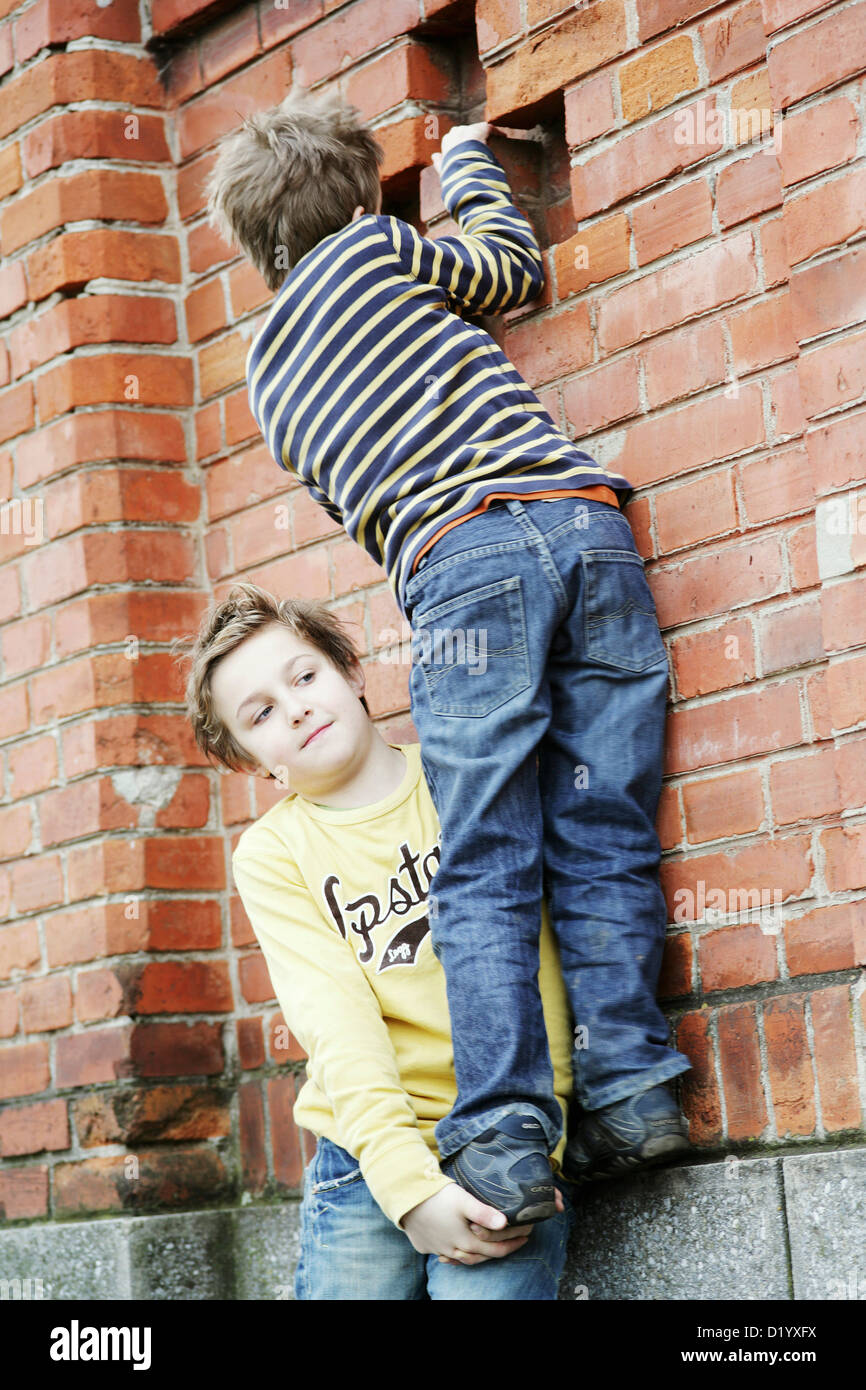 Boy giving friend a bunkup over a wall Stock Photo Alamy