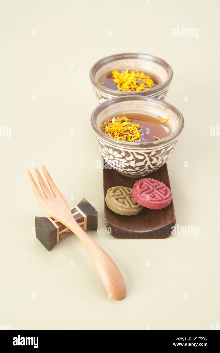 yellow chrysanthemums flower tea in mug cups with Korean finger cake and a fork Stock Photo