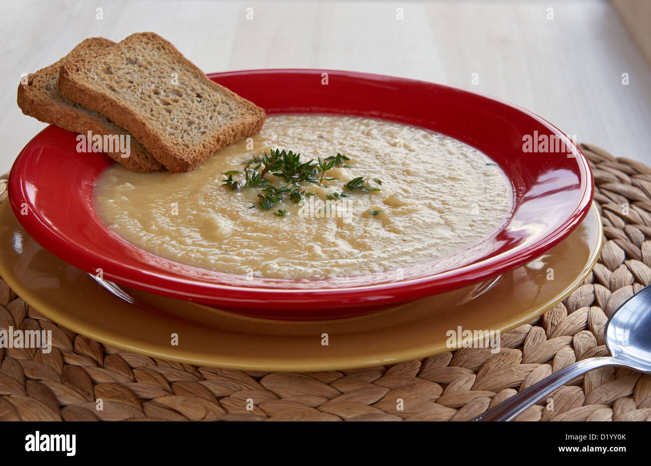 Hot cream of celeriac soup in a red plate on the table with croutons. Best for autumn cold. Stock Photo
