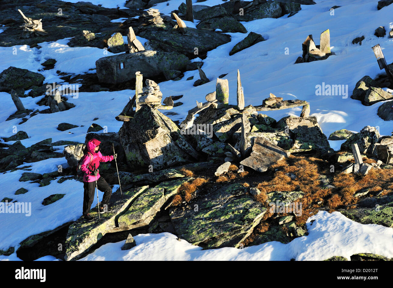 Woman walking through snow covered rocks and cairns, Peterskoepfl, Zillertal range, Zillertal, Tyrol, Austria Stock Photo