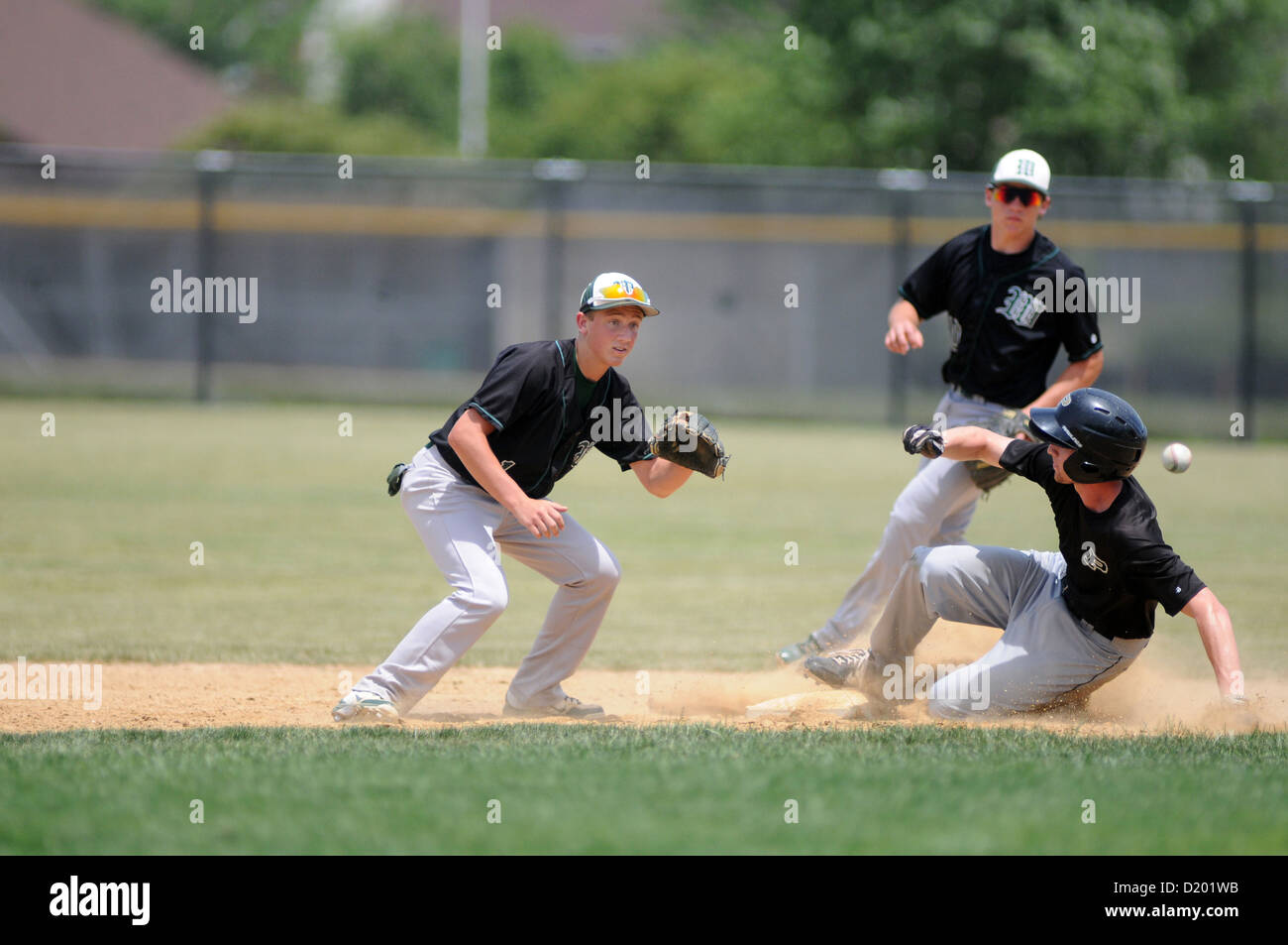 Baseball Base runner slides in safely with a steal of second base as the opposing shortstop awaits the tardy throw. USA. Stock Photo
