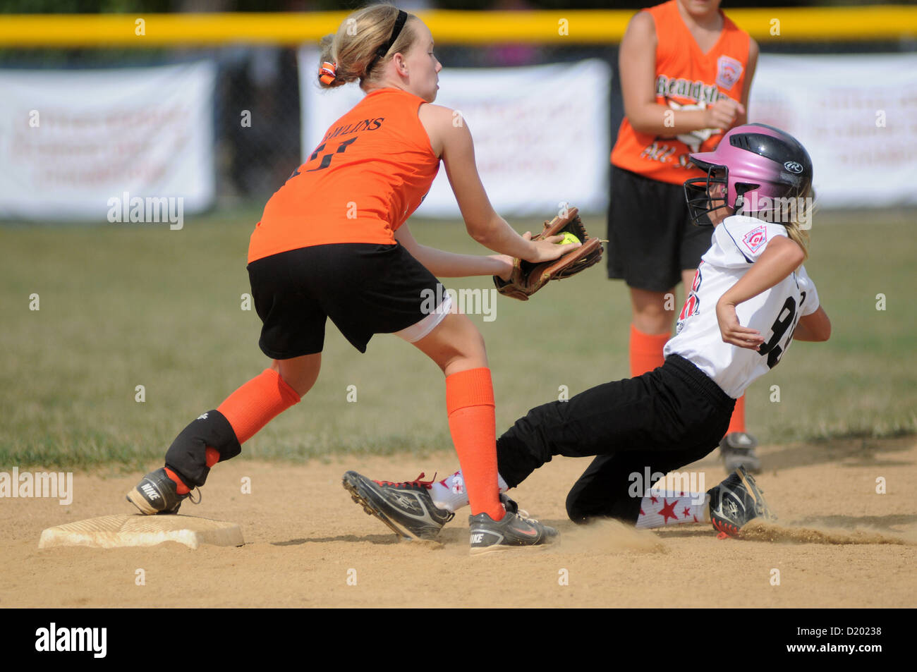 Softball Infielder tags a base runner as she slides into second base Little League game Stock Photo